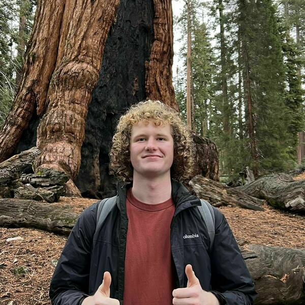 Picture of undergraduate student Charles Sander in front of a big redwood tree.